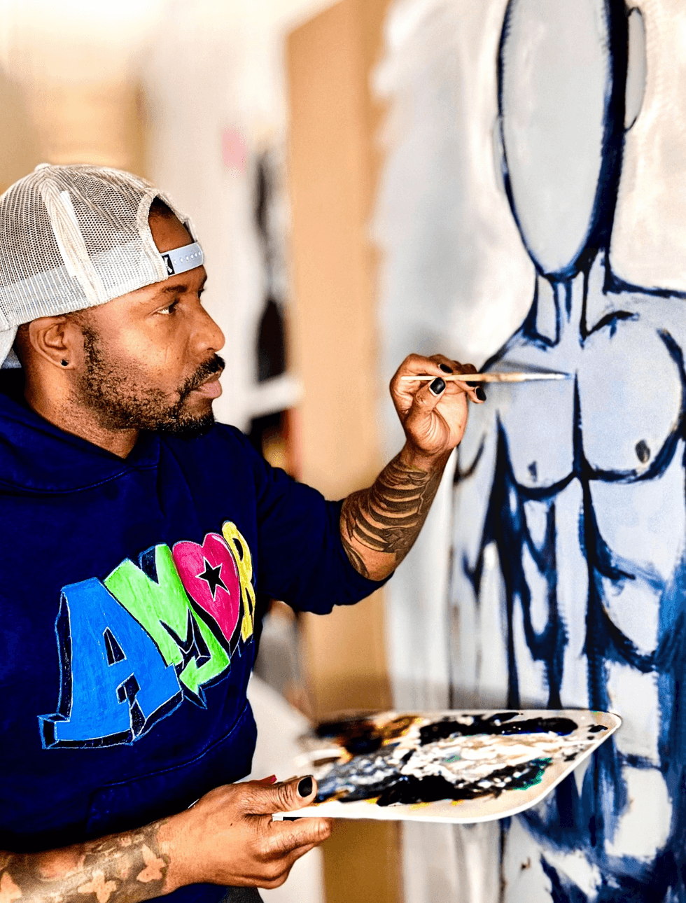The artist paints a monochrome figure with bold outlines and defined musculature on a large canvas