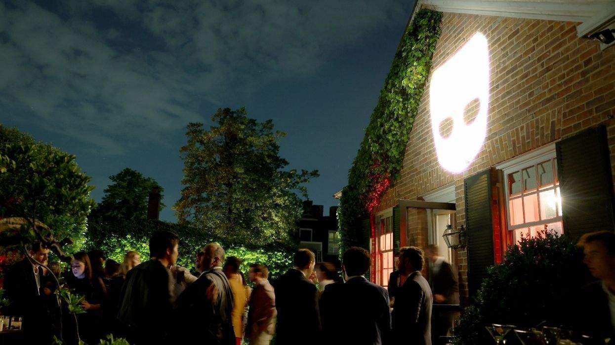 the grindr logo displayed on the side of a building with people standing in the foreground