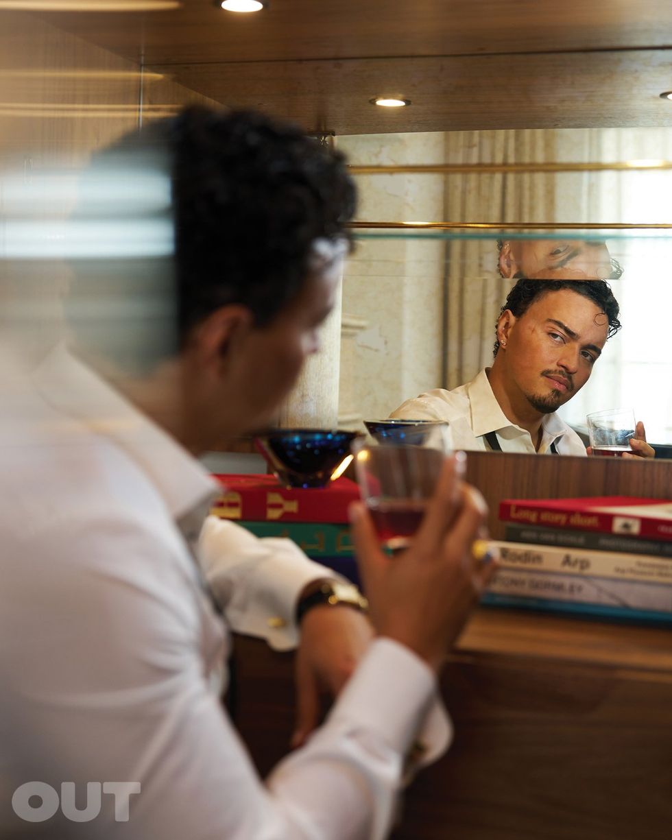 Tonatiuh with a drink looking into a mirror