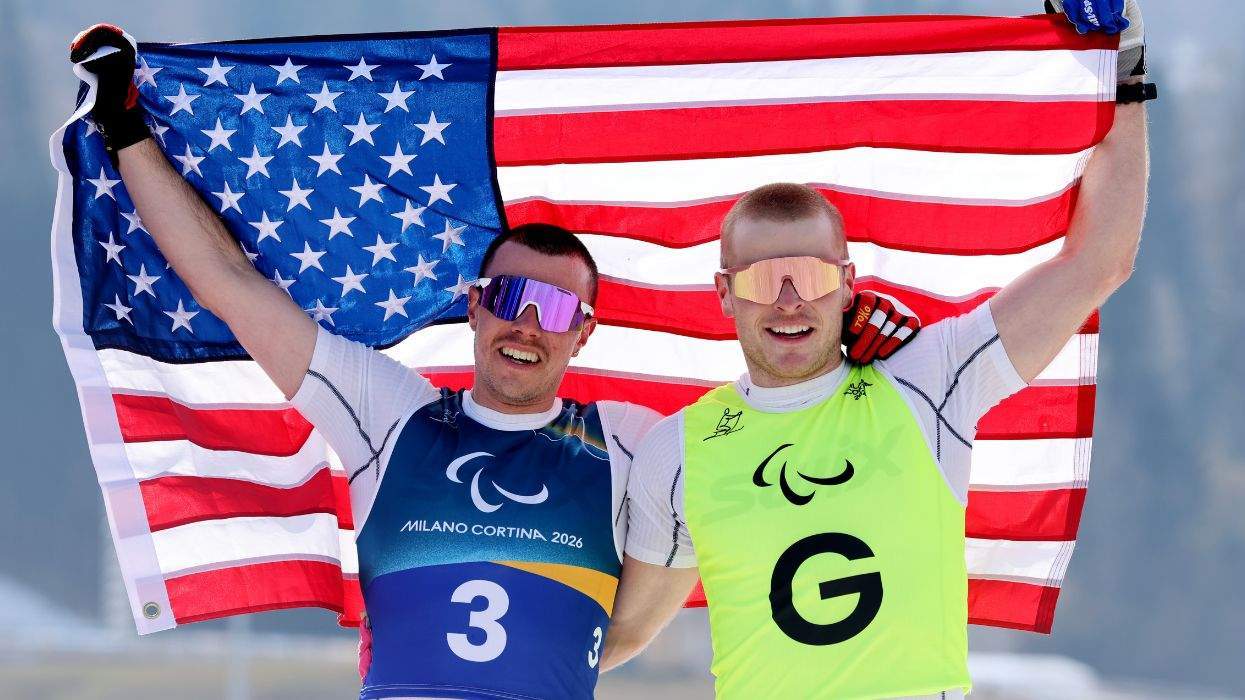 Two athletes celebrate with a USA flag at the Milano Cortina 2026 event.
