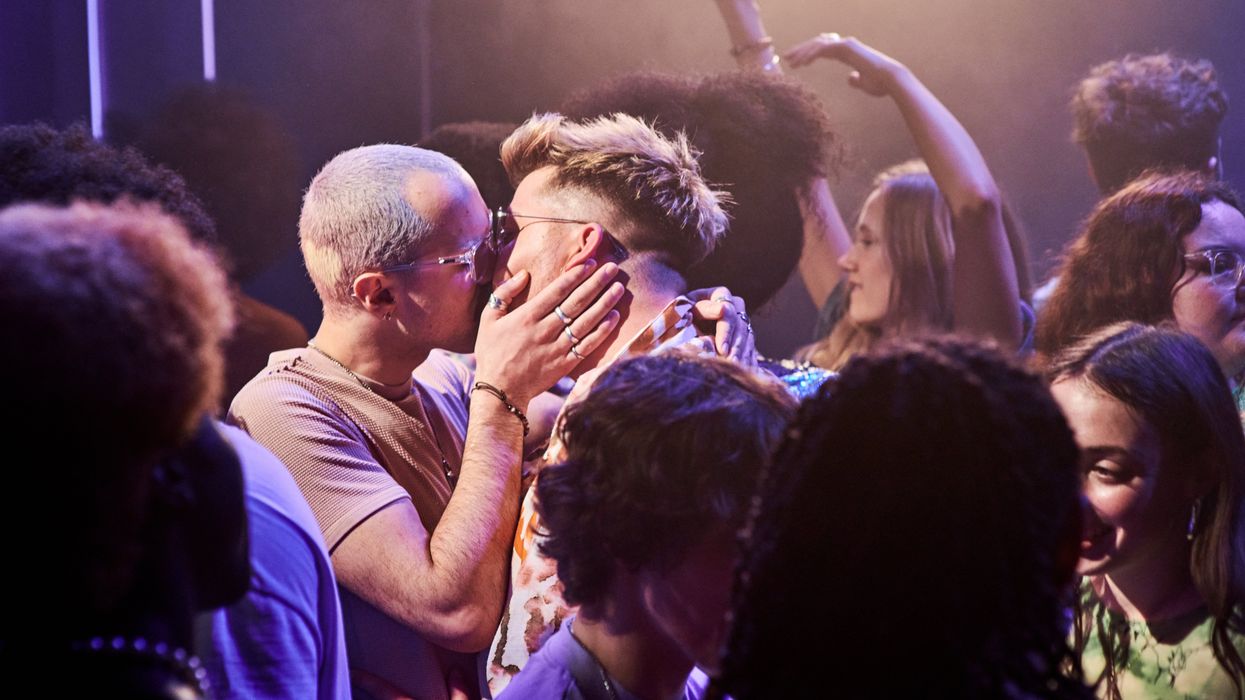 Two gay men kissing in the middle of the dance floor