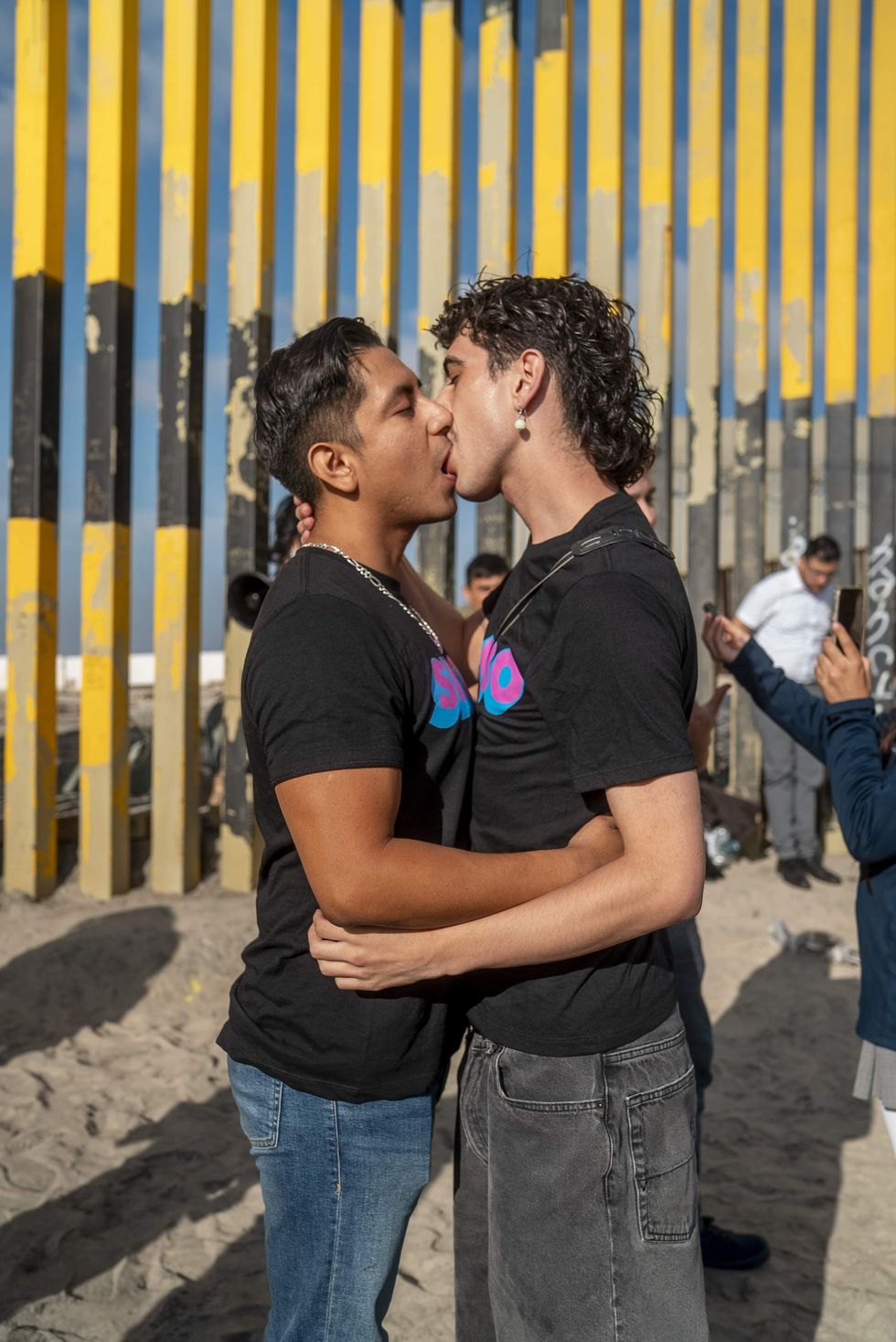 Two men kiss in front of U.S.-Mexico border