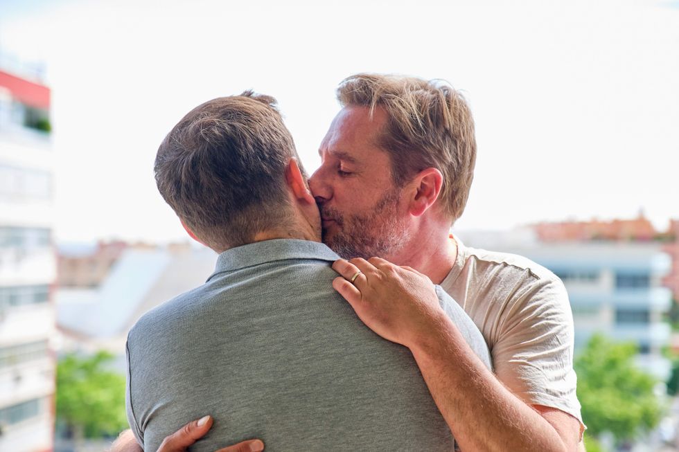 Two men kissing, one has his back to the camera