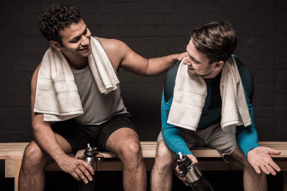 Two men sitting on a bench in a locker room