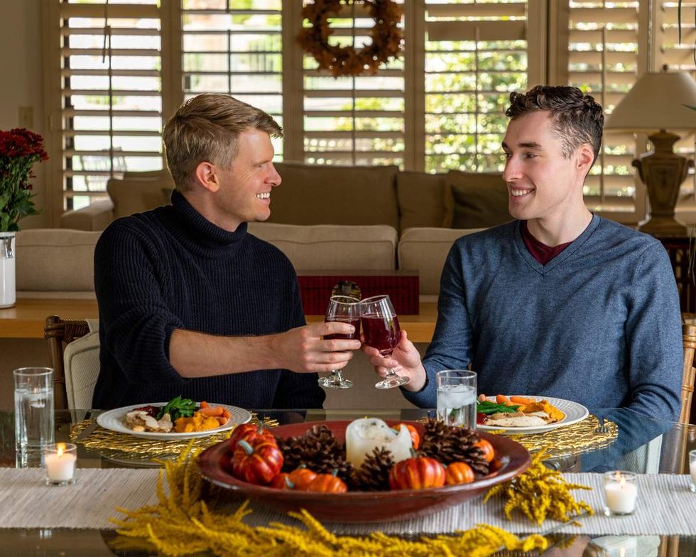 two men toast each other over a thanksgiving dinner