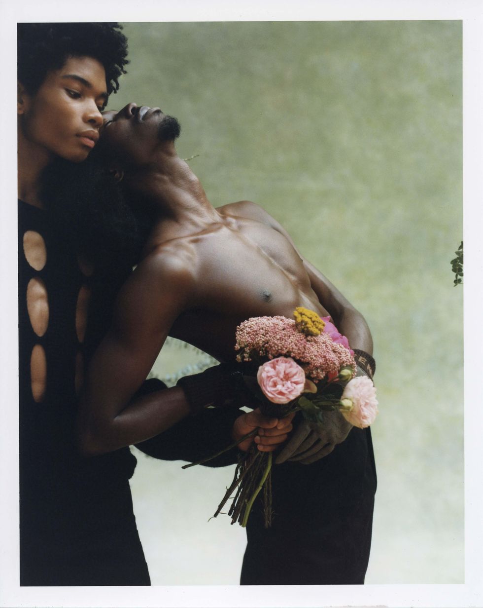 Two models dressed in Fendi holding flowers.