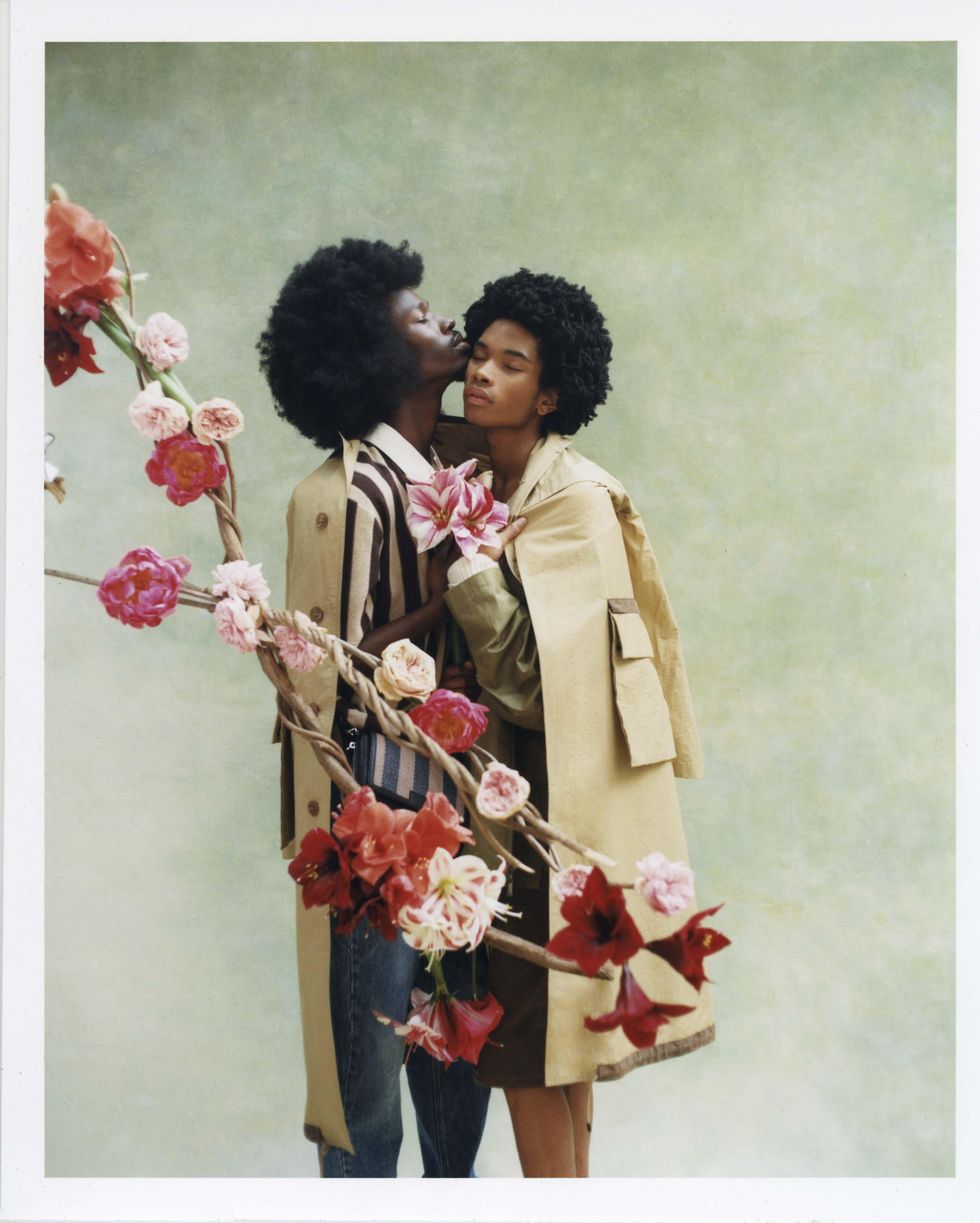 Two models dressed in Fendi holding flowers.