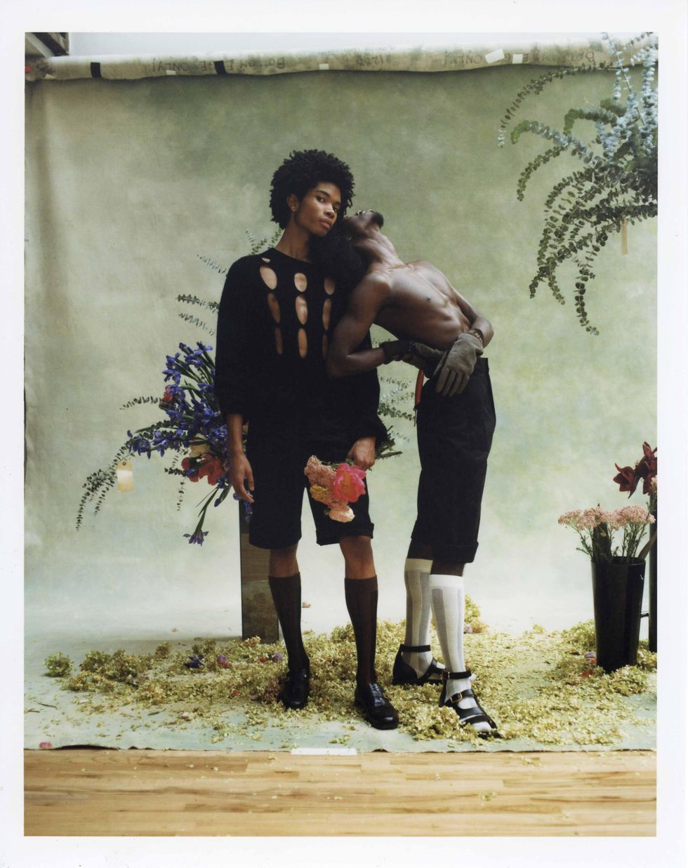 Two models dressed in Fendi holding flowers.