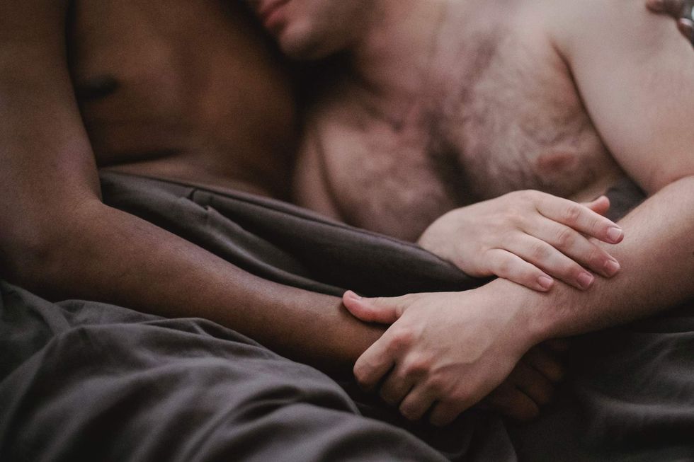 Two people holding hands in bed