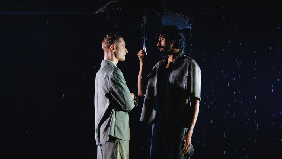 Two people standing under an umbrella