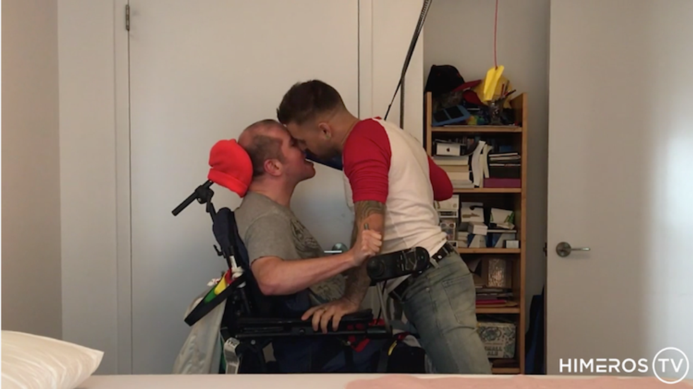 Two porn performers, one in a wheelchair, kissing.