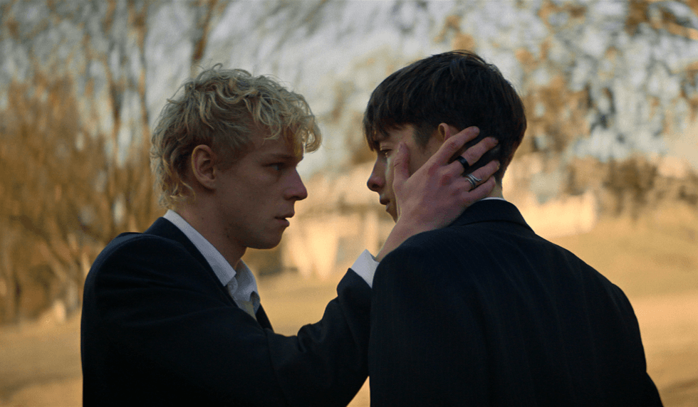 Two teenage boys in school uniforms face one another outdoors in a scene from Leviticus.