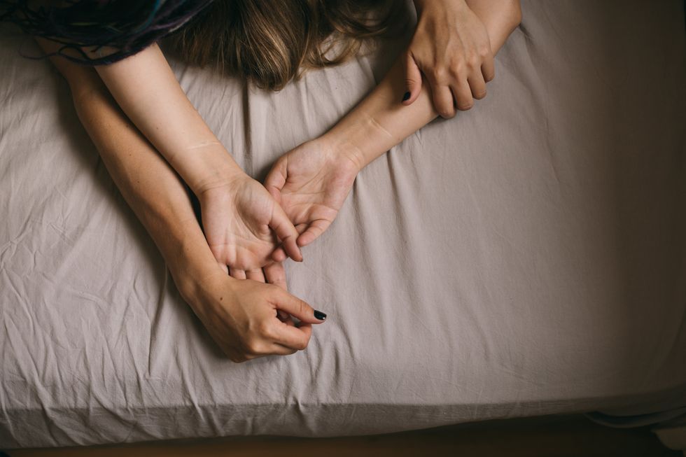 Two women grasping hands in bed