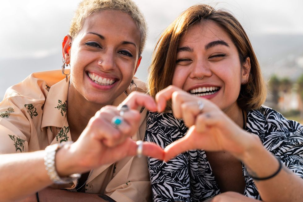 Two women making a heart symbol with their hands