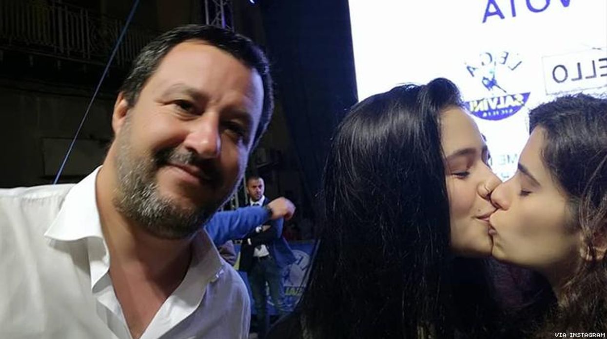 Two women photobomb anti-gay Italian politician with same-sex kiss selfie.