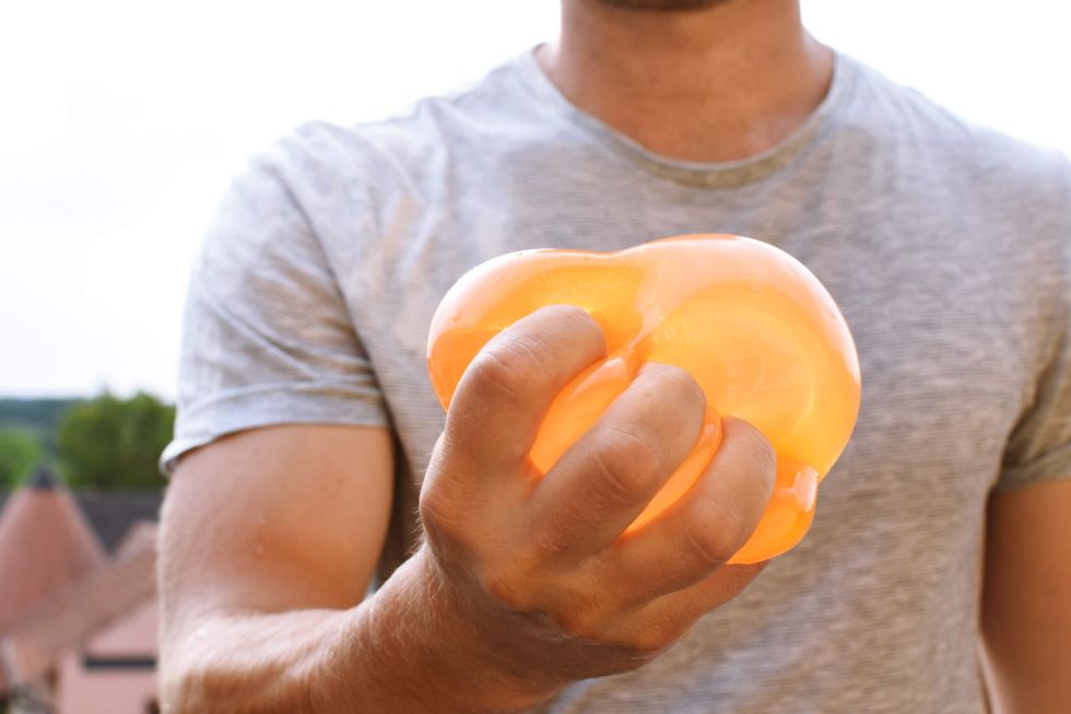 \u200bA man squeezing a water balloon.