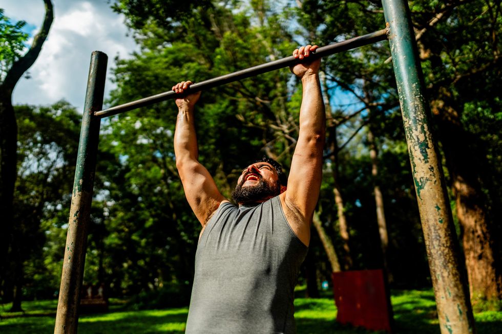 \u200bMan doing a pull up in the park.