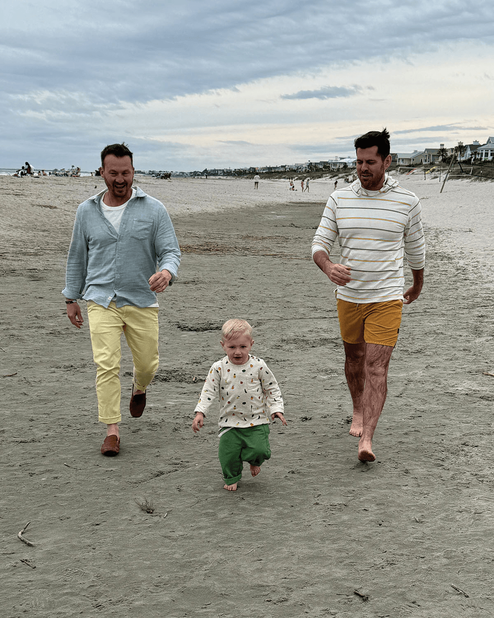 \u200bPJ Wilson, Stephen Walker, and their son, Theo, take a walk on the beach