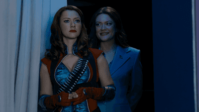 Valorie Curry as Firecracker stands in costume beside Colby Minifie as Ashley Barrett in a dark hallway scene from The Boys.