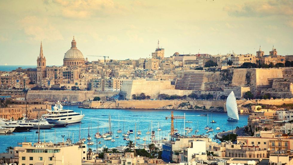 View of Valletta, Malta, featuring historic limestone buildings, harbor waters, sailboats, and the city\u2019s fortified walls