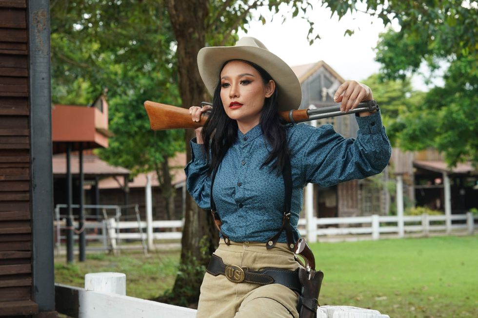 Woman dressed as a cowgirl holding a gun