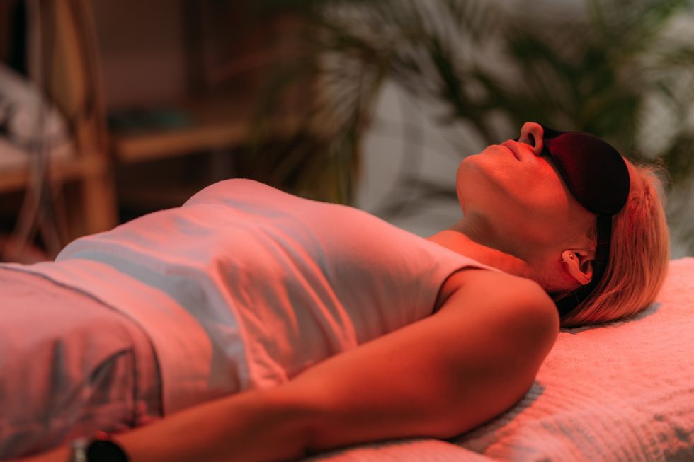Woman lying down with an eye mask on using red light therapy