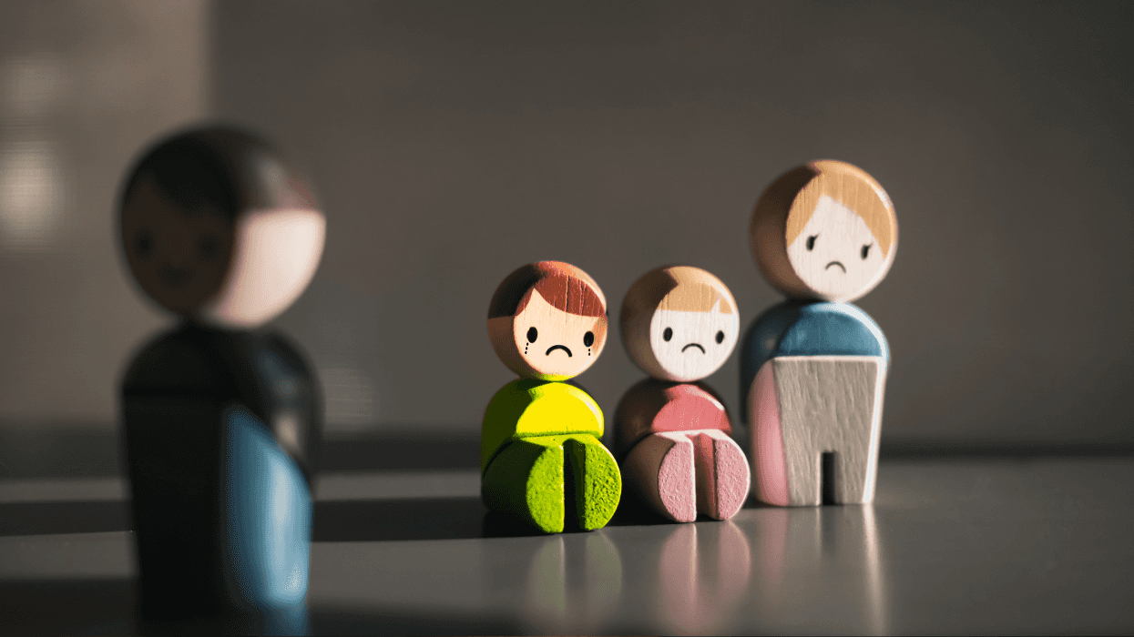 Wooden figures representing a broken family, with sad children and distant parents