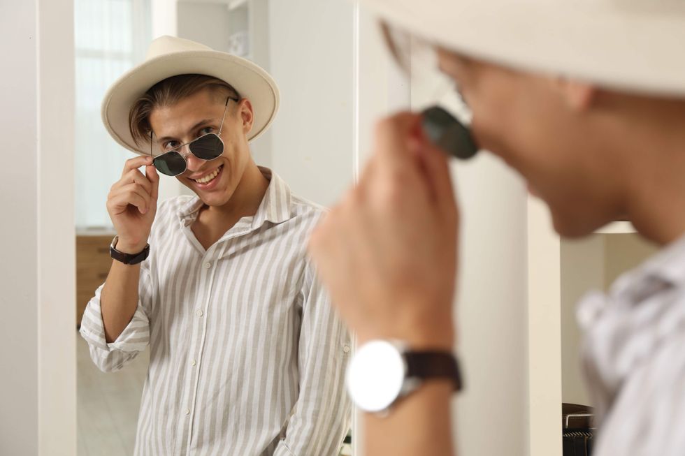 Young man with sunglasses looking in the mirror