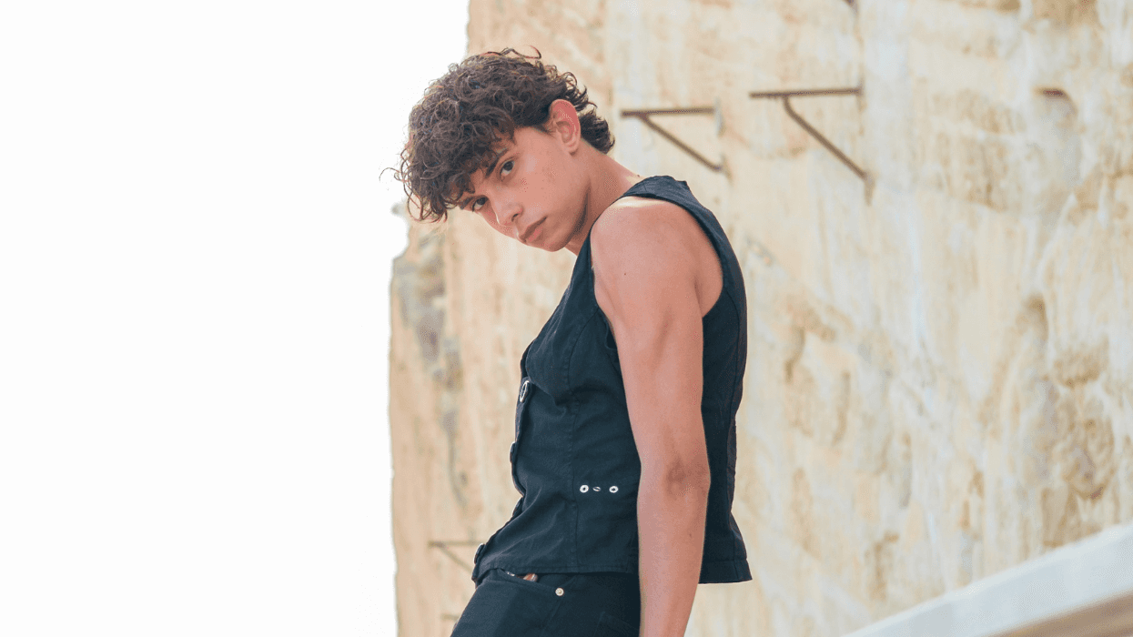 Young person leans against a rail and looks at the camera