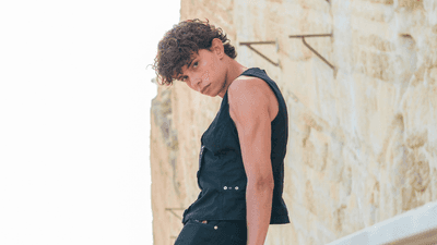 Young person leans against a rail and looks at the camera