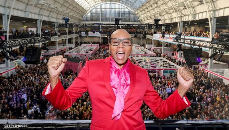RuPaul at Drag Con UK on a balcony above thousands of dancers. 