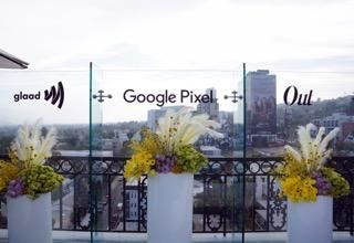 panoramic view of LA skyline with Glaad Google and Out Magazine logos each with a floral arrangement