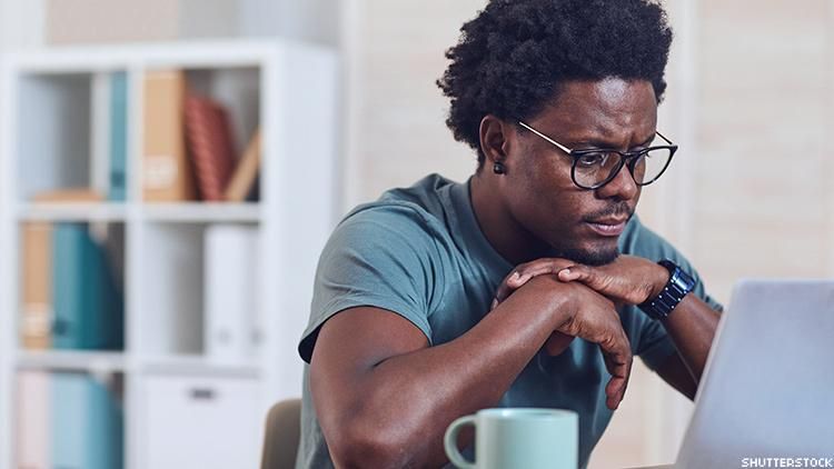 A Black man sitting at a laptop.