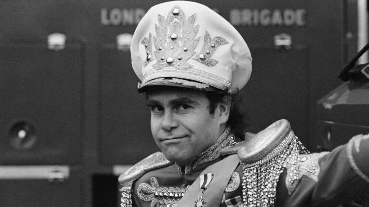 Elton John wears an oversized military hat.